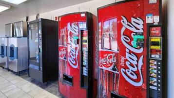 A row of vending machines with Coca-Cola branding, including a dollar bill dispenser and a drink selection panel.