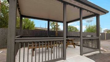 A covered outdoor seating area with a table and benches.