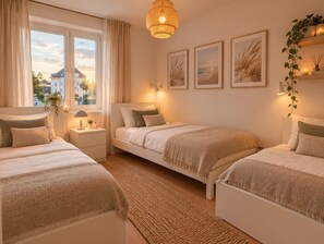 Ein Schlafzimmer mit zwei Betten, einem großen Fenster und einer hängenden Leuchte.