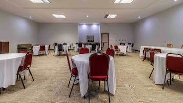 A conference room with round tables, red chairs, and carpeted flooring.