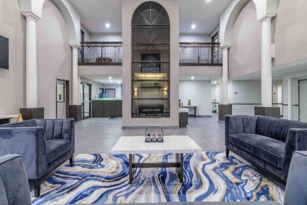 A spacious lobby with a marble-patterned floor, two sofas, a coffee table, and a fireplace.