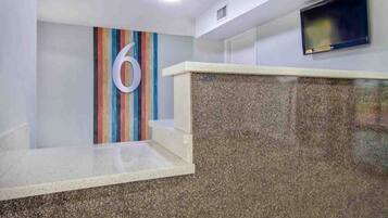 A reception area with a large number '6' on the wall, a flat-screen TV mounted on the wall, and a granite counter.
