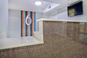 Une salle d’attente avec un grand chiffre « 6 » affiché sur le mur, un téléviseur à écran plat fixé au mur et un comptoir en granit.