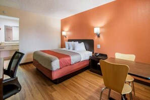 Une chambre d’hôtel comprenant un lit, une table de chevet, une chaise et une petite table avec une autre chaise.