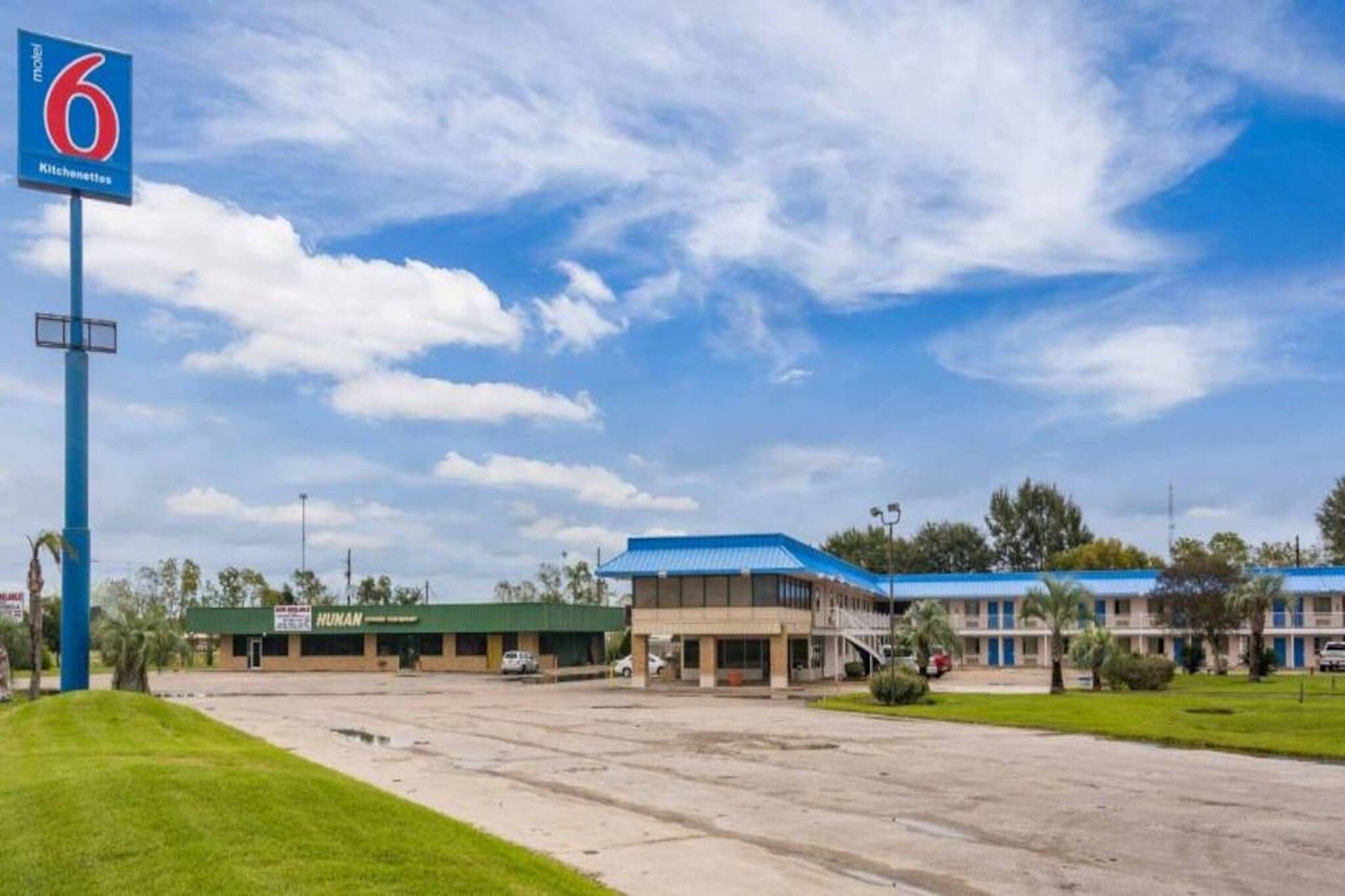 A motel with a large parking lot, a green building labeled 'HUNAN,' and a blue-roofed structure.