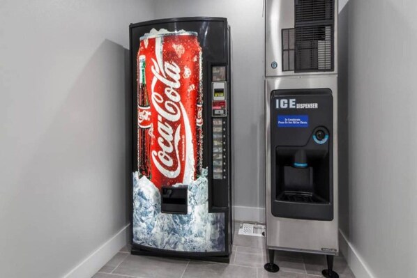 Un distributeur automatique de Coca-Cola avec un distributeur de glaçons à côté.