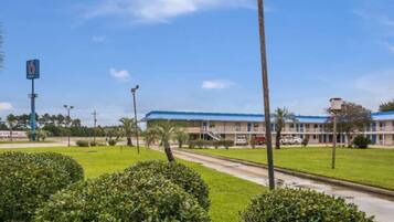 A motel with a blue roof, a parking lot, and a clear sky.