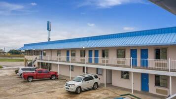 A motel with a blue roof, a parking lot, and a handicap-accessible parking space.