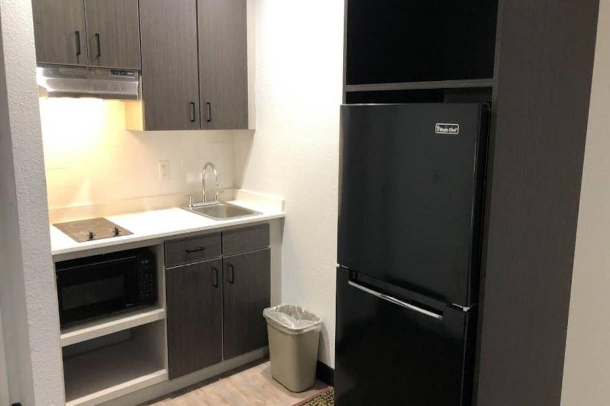 A compact kitchen with a built-in oven, a sink, and a black refrigerator.