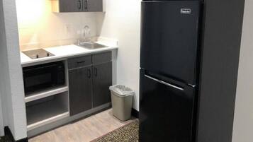 A compact kitchen with a black refrigerator, a microwave, and a sink.