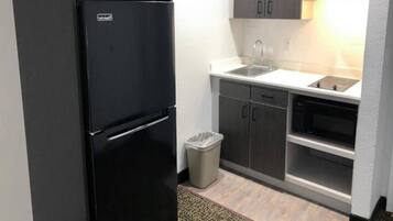 A compact kitchen with a black refrigerator, a sink, and a microwave.