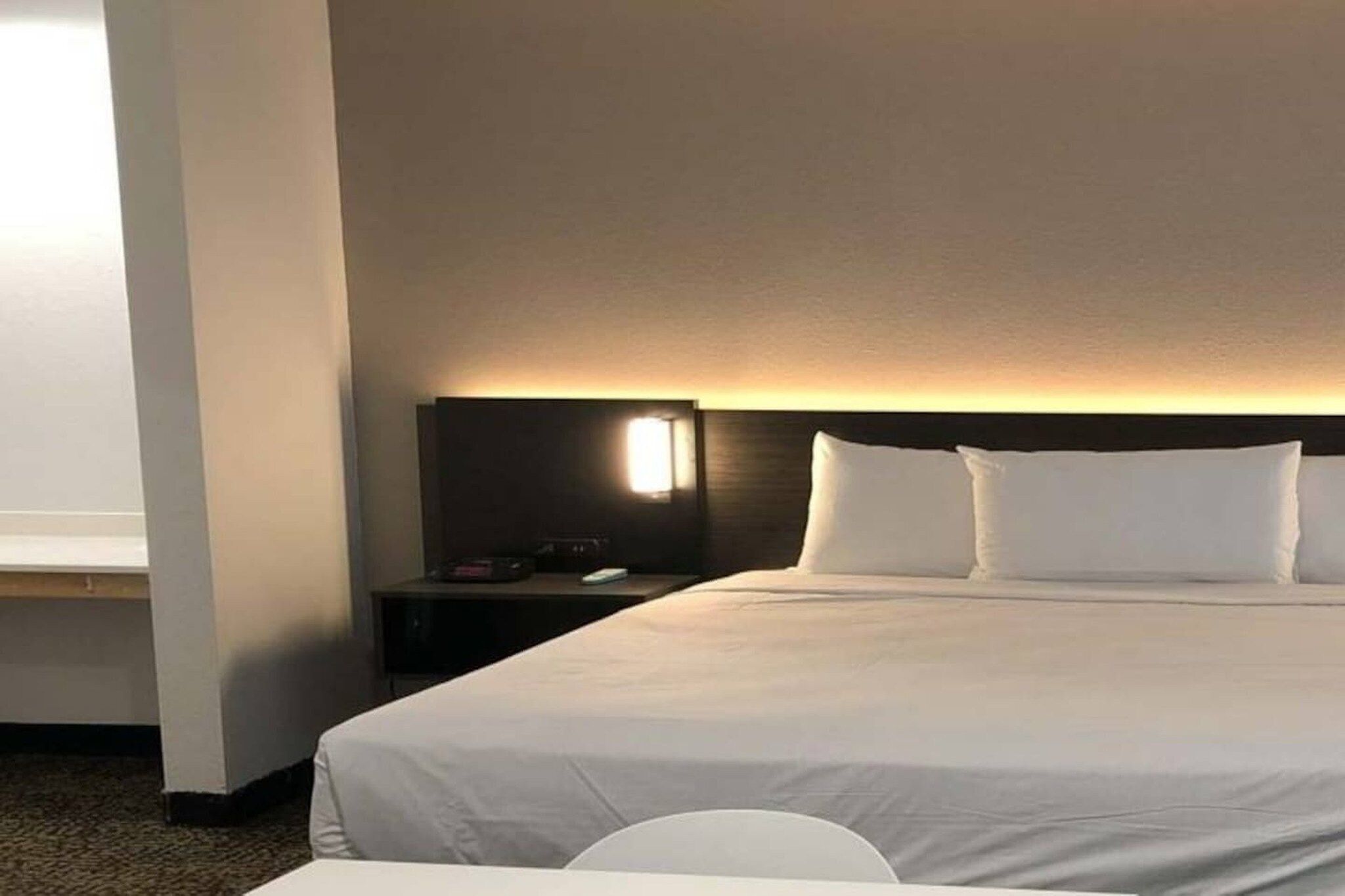 A hotel room with a large bed, a bedside table, a lamp, and a window.