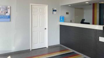 A reception area with a white door, a counter with a mirror, and a colorful striped carpet.