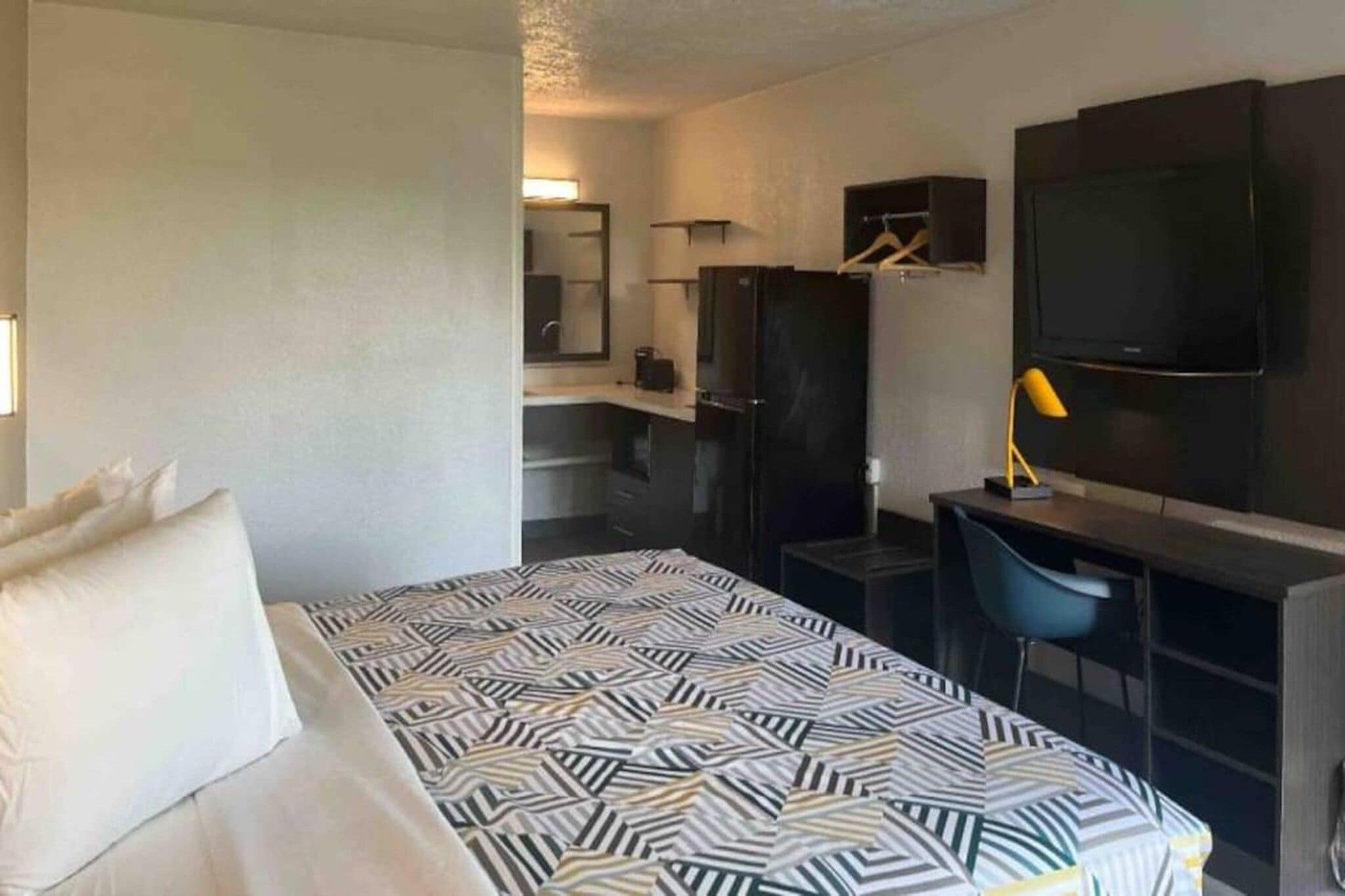 Hotellihuone, jossa on sänky, työpöytä, tuoli, televisio ja vaatekaappi.