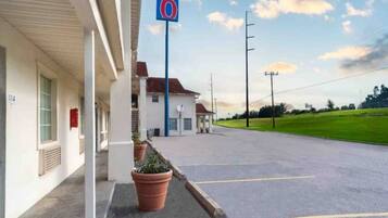 Un motel con un estacionamiento, un edificio con un letrero con el número '114', e indicación de que es el motel número '6'.