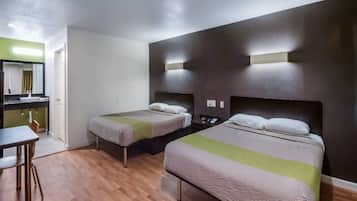 A hotel room with two beds, a desk, and a mirror.