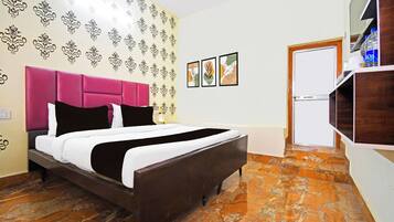 A room with a bed, a wardrobe, a door, and a wall with patterned wallpaper.