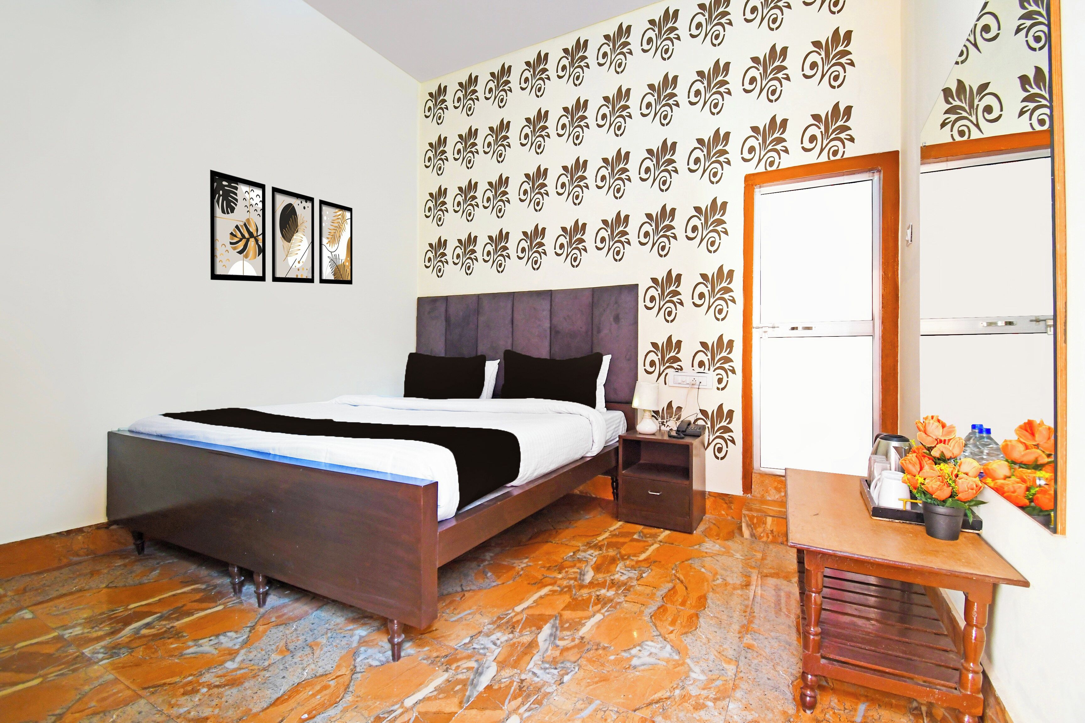 A bedroom with a bed, nightstand, and a small table with flowers.