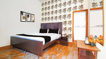 A bedroom with a bed, nightstand, and a small table with flowers.