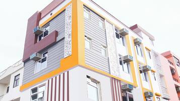 Un immeuble à plusieurs étages doté de balcons, de grandes fenêtres et d’une façade remarquable aux couleurs jaune et blanche.