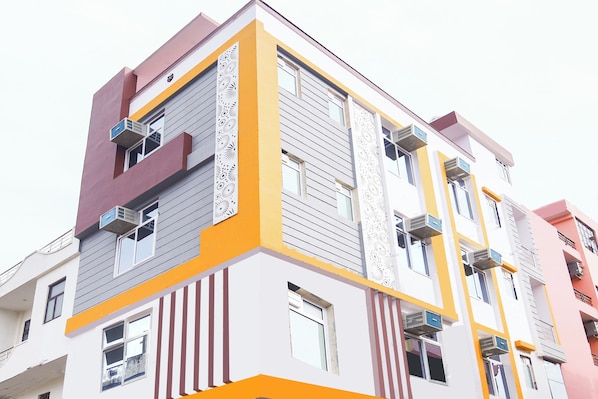 Un edificio de varios pisos con balcones, ventanas amplias y una fachada distintiva en colores amarillo y blanco.