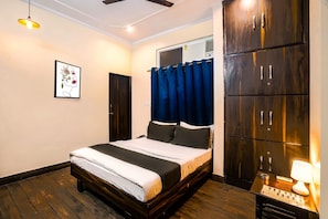 Un dormitorio con cama, armario, ventilador de techo, aire acondicionado de pared y una obra de arte enmarcada.