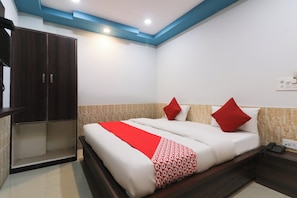 Una camera d'albergo con un letto, un armadio e un comodino con il telefono.