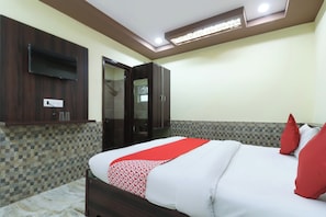 Una camera d'albergo con un letto, un armadio, uno specchio e una televisione a parete.