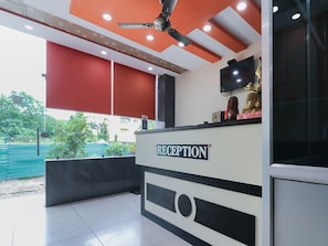 Un'area reception con ventilatore a soffitto, televisore e un cartello con su scritto 'RECEPTION'.