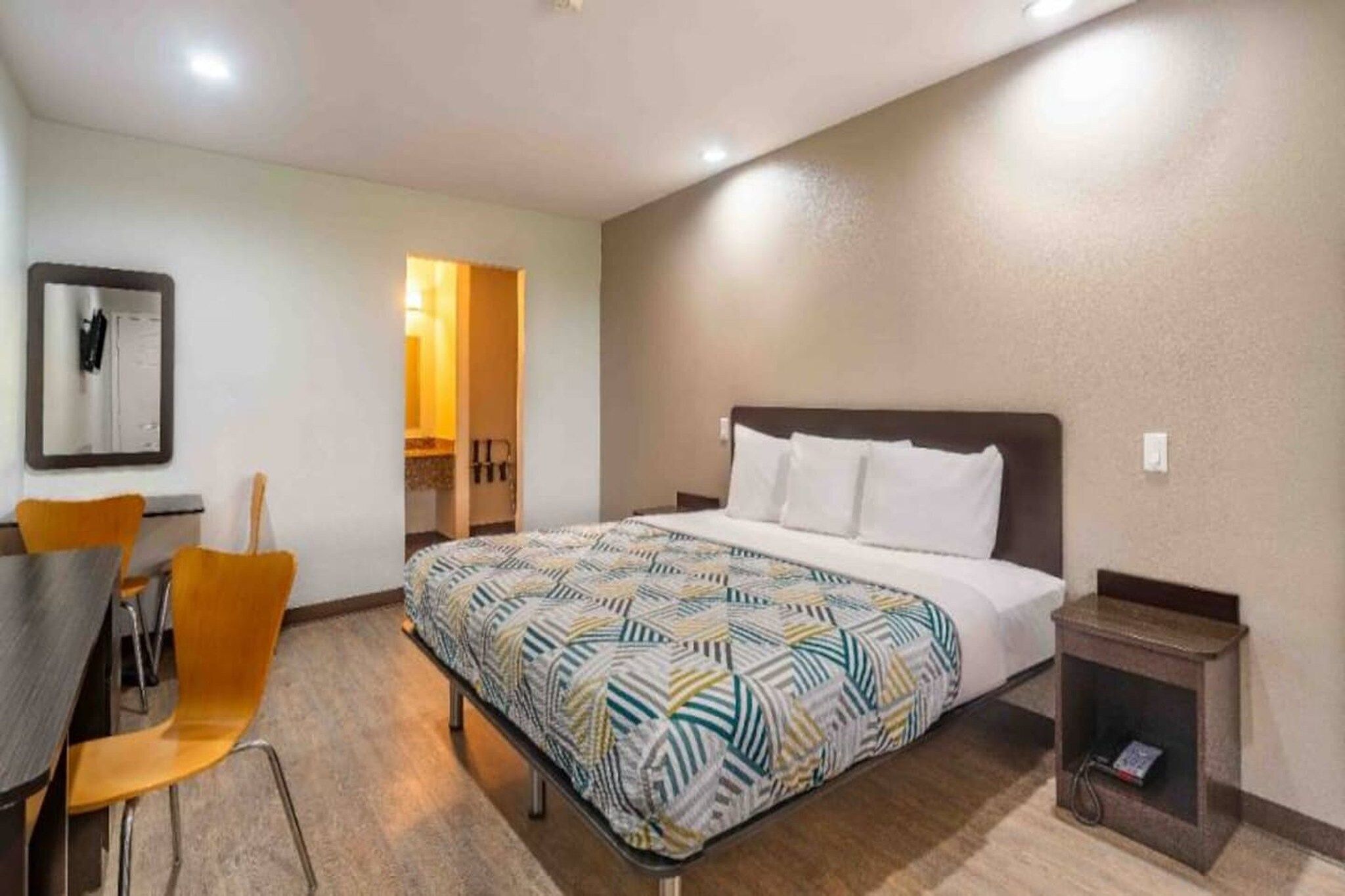 Una camera d'albergo con un letto, una scrivania e una sedia.