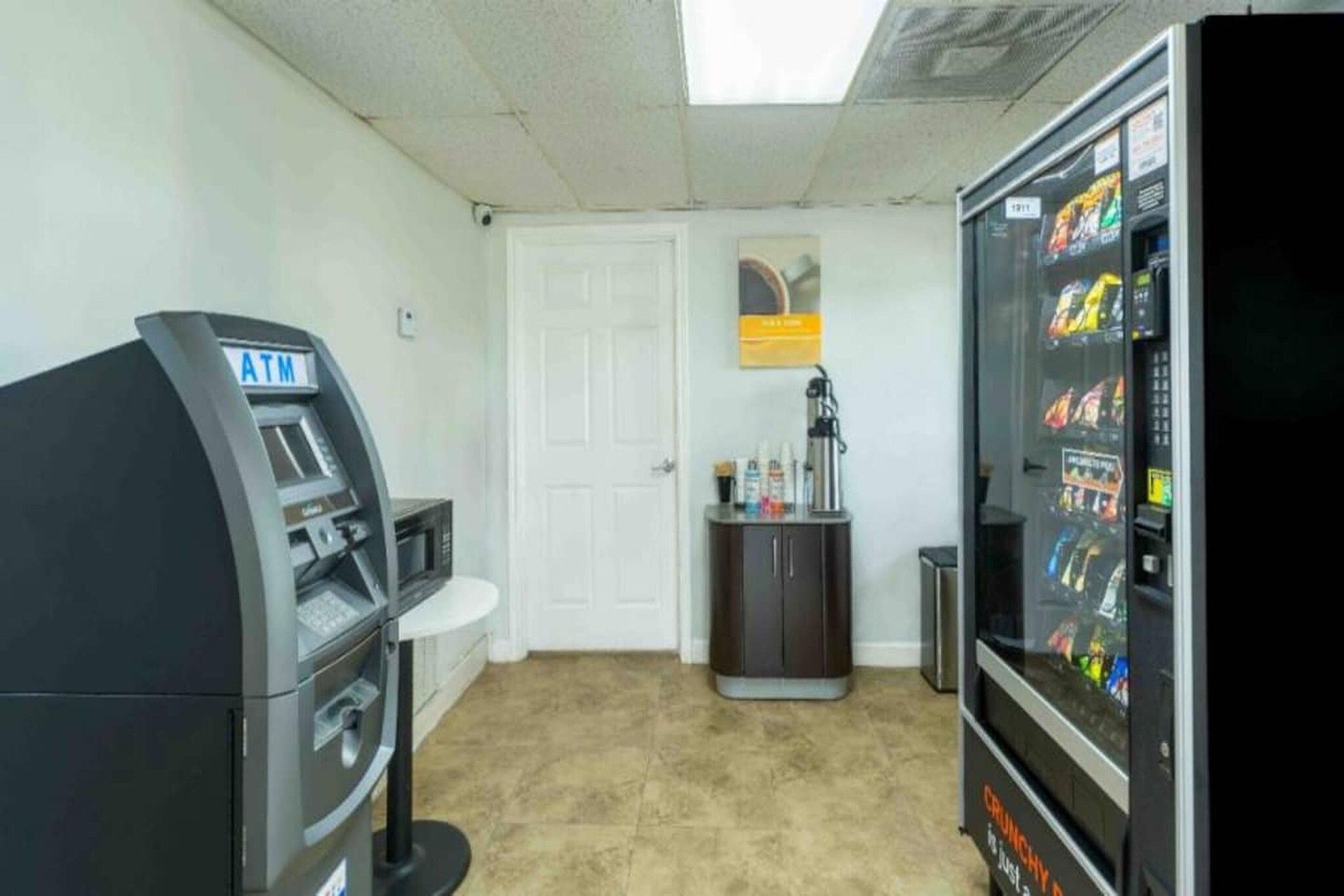 A room with an ATM, a vending machine, a door, and a cabinet.