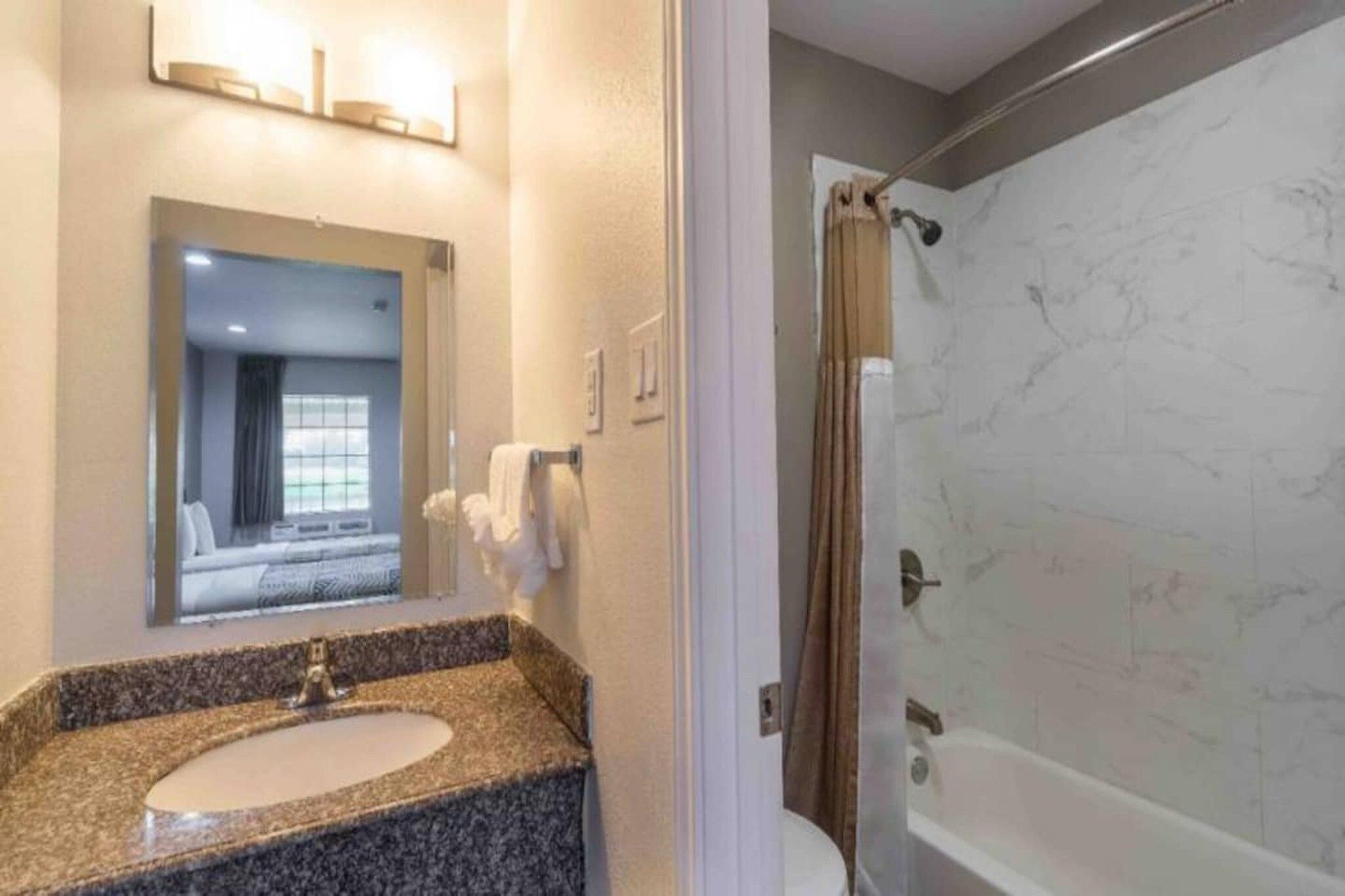 A bathroom with a sink, mirror, and shower curtain.
