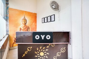 En receptionsdisk med en skylt som visar texten ”OYO” och en Buddha-staty i bakgrunden.