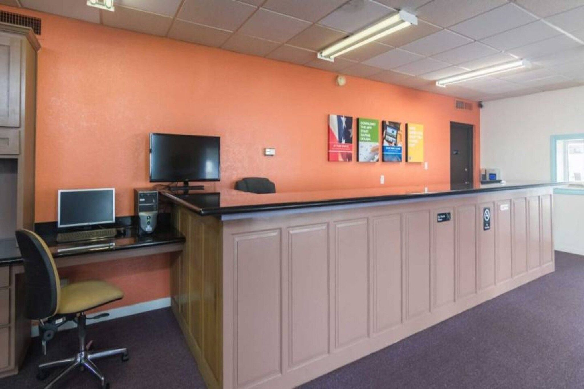 A reception area with a desk, computer, and chair.