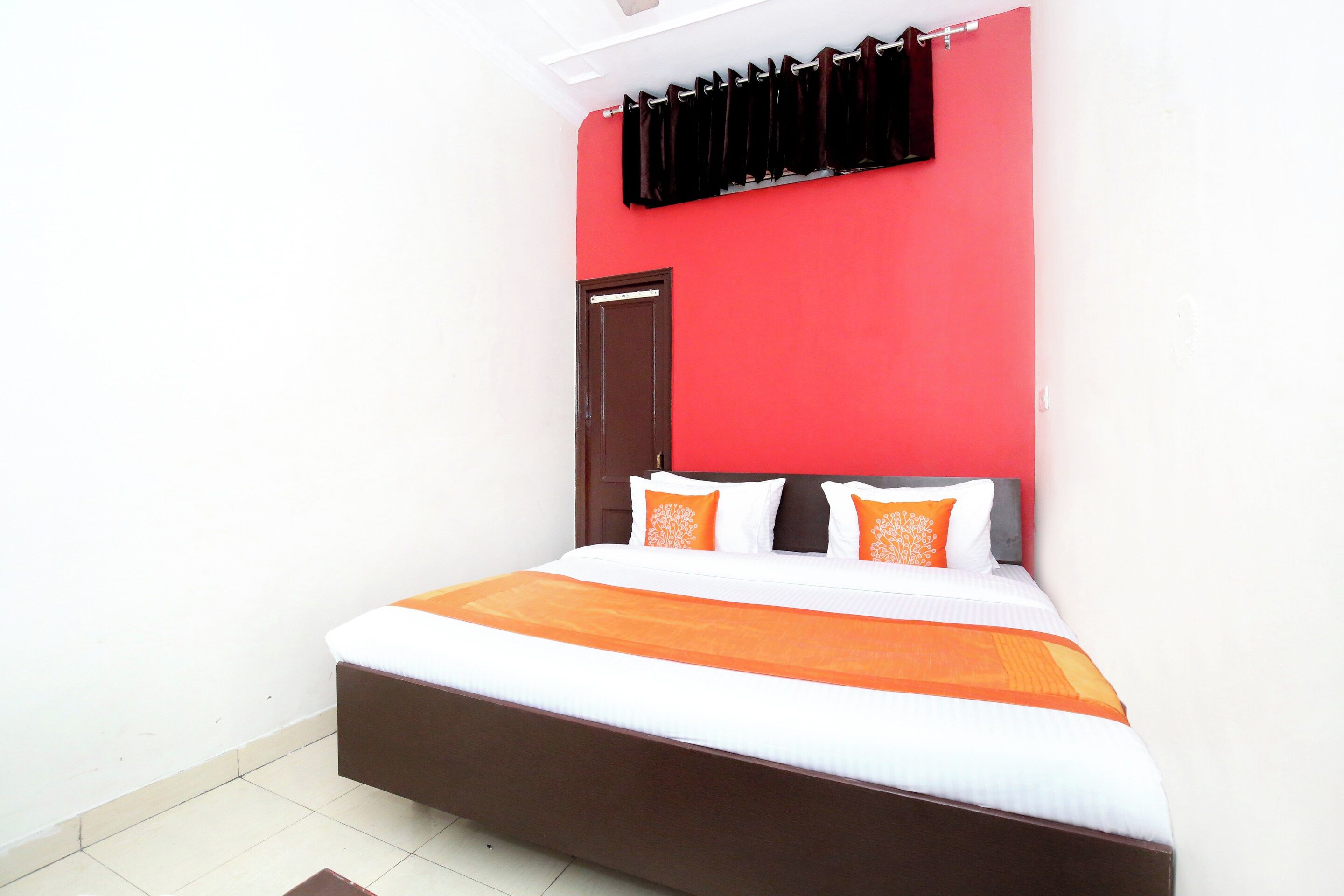 A bedroom with a bed, a red wall, and a door.