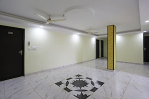 A corridor with a patterned floor, ceiling fans, and doors. - Hotel O Lime Wood (Dehradun)