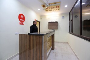 A reception desk with a wooden finish, a ceiling fan, and a clock on the wall. - Hotel O Lime Wood (Dehradun)