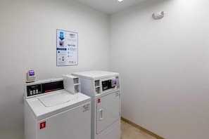 A laundry room with two front-loading washing machines and a wall-mounted instruction sign. - 1 Queen Bed | Micfridge | NSMK (Austin)