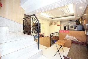 A hotel interior with a staircase, a dining area, and a kitchenette. - Hotel O Le Bon Ton (Ludhiana)