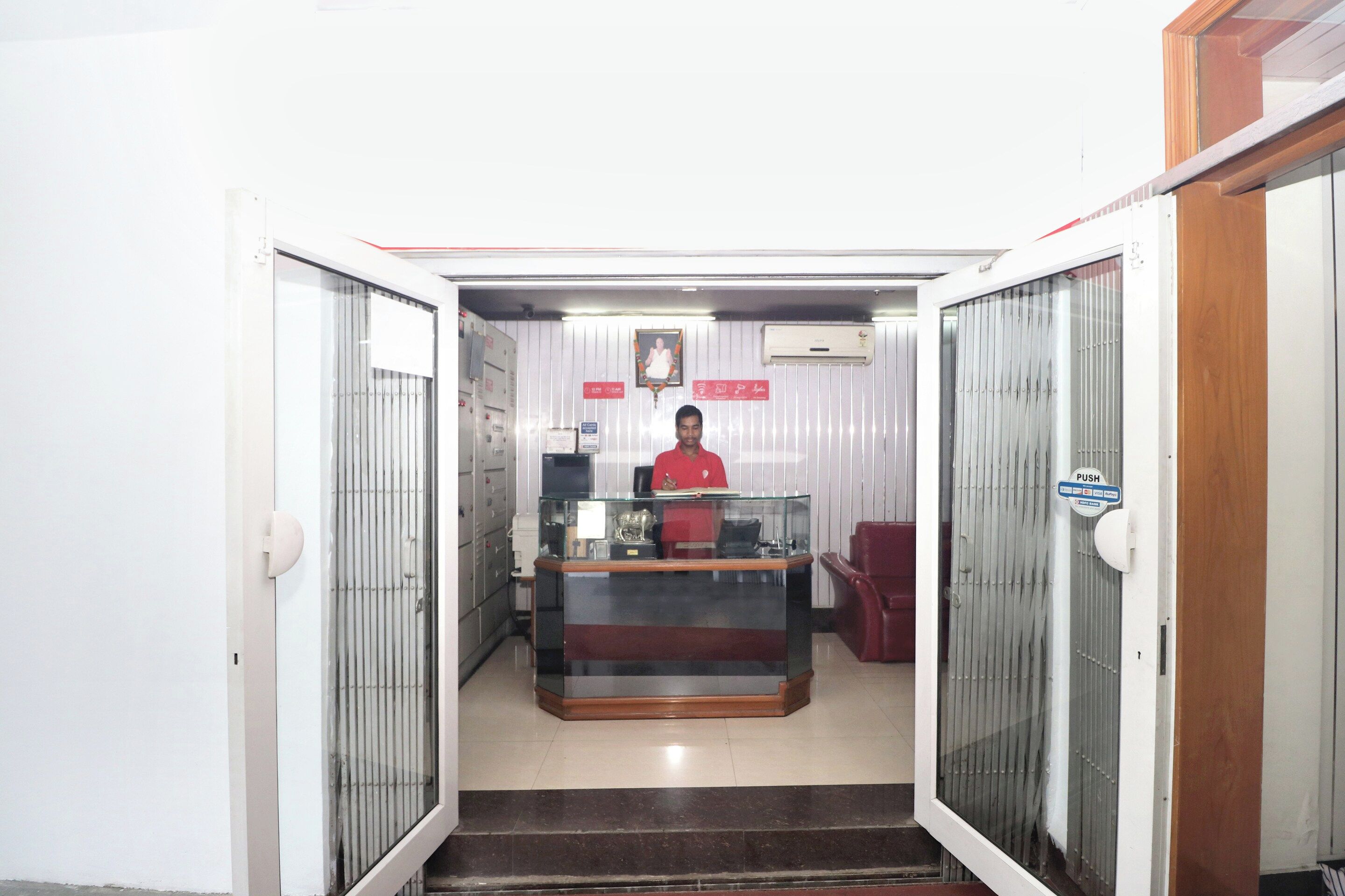 A reception area with a receptionist desk, a glass display case, and a staircase leading to an upper floor.