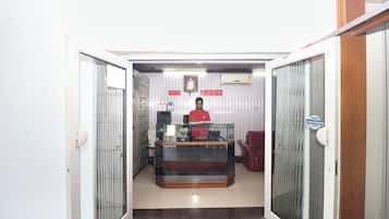 A reception area with a receptionist desk, a glass display case, and a staircase leading to an upper floor.