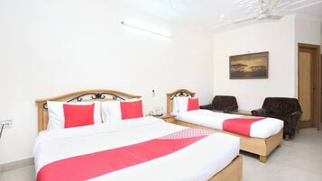 A hotel room with two beds, a ceiling fan, a painting, and a door.