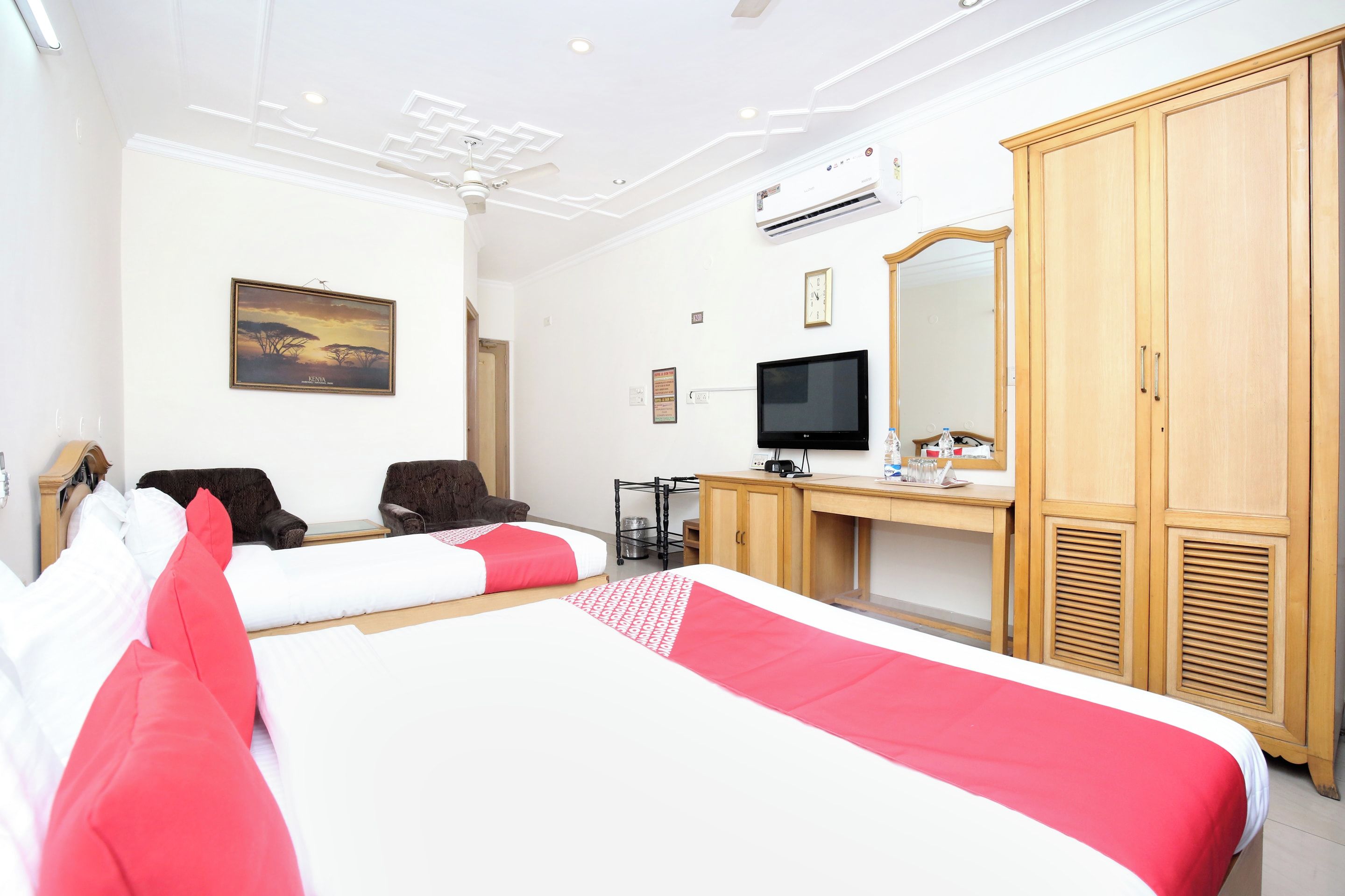 Une chambre d’hôtel comprenant un lit, deux chaises, un bureau avec un ordinateur, une télévision et une armoire.