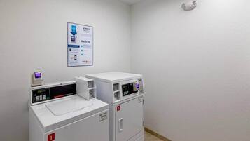 A laundry room with two front-loading washing machines and a wall-mounted instruction sign.