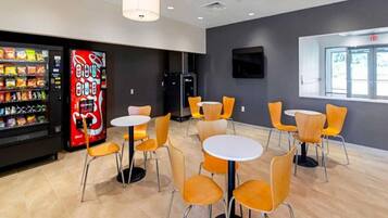 A modern indoor space with vending machines, tables, and chairs.