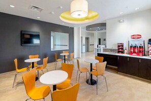 Un intérieur moderne avec des tables rondes et des chaises orange, un téléviseur à écran plat et un coin café.