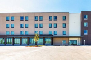 Un hôtel moderne, avec une façade plate, de nombreuses fenêtres et un parking situé à l’avant.