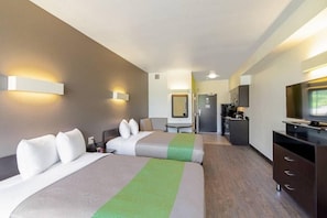 A hotel room with two beds, a desk, a television, and a mirror. - 2 Full Beds | Kitchen, Non-Smoking (Austin)