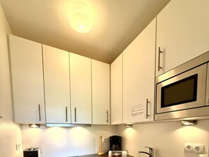 Eine Küche mit weißen Schränken, einem Bosch-Toaster, einer Kaffeemaschine und einer Mikrowelle.