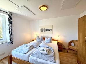 Ein Schlafzimmer mit einem Bett, Nachttischen, einem Sessel und einem Kleiderschrank.